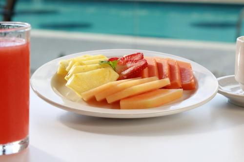 a plate of fruit and vegetables on a table with a drink at Holiday Inn Express & Suites - Ensenada Centro by IHG in Ensenada