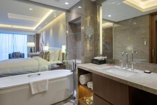 uma casa de banho com uma cama, uma banheira e um lavatório. em Intercontinental Jinan City Center, an IHG Hotel em Jinan