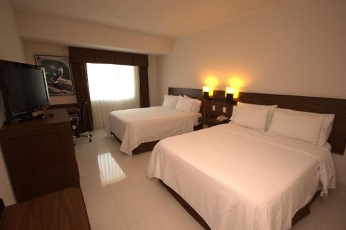 a hotel room with two beds and a flat screen tv at Holiday Inn Express Tuxtla Gutierrez La Marimba by IHG in Tuxtla Gutiérrez