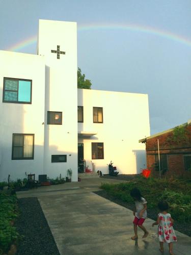 two little girls playing in front of a white building at Tree House Café & Homestay in Tongluo