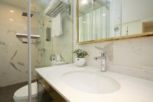 a bathroom with a sink and a toilet and a mirror at Shanghai Meego Qingwen Hotel in Shanghai