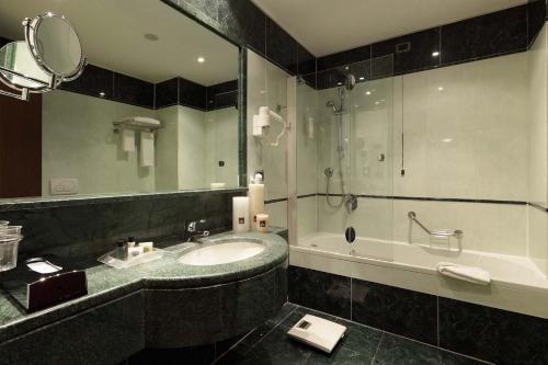 a bathroom with a sink and a tub and a mirror at Holiday Inn Turin Corso Francia, an IHG Hotel in Turin