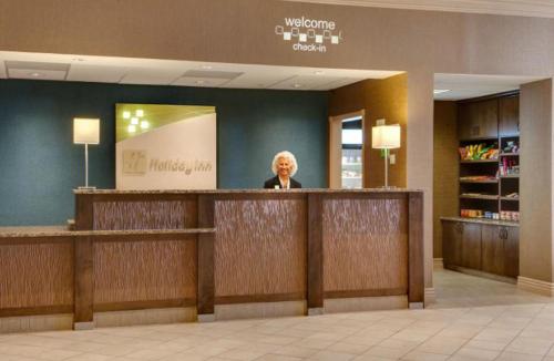 a man standing at a reception counter in a store at Holiday Inn Hotel & Suites Overland Park-West by IHG in Overland Park