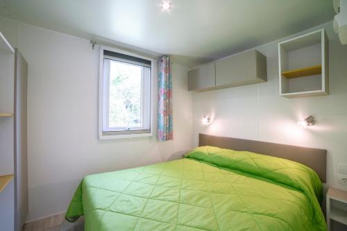 a bedroom with a green bed and a window at Camping Baia Verde in Manerba del Garda