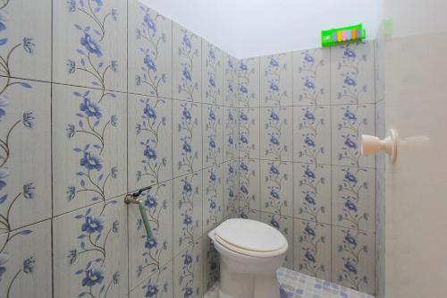 a bathroom with a toilet and blue flowers on the wall at SPOT ON 2022 Darman Family Residence Syariah in Banyuwangi