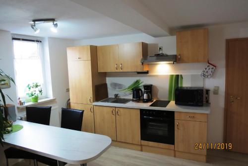 a kitchen with wooden cabinets and a table and a microwave at Am Mehliser Markt in Zella-Mehlis