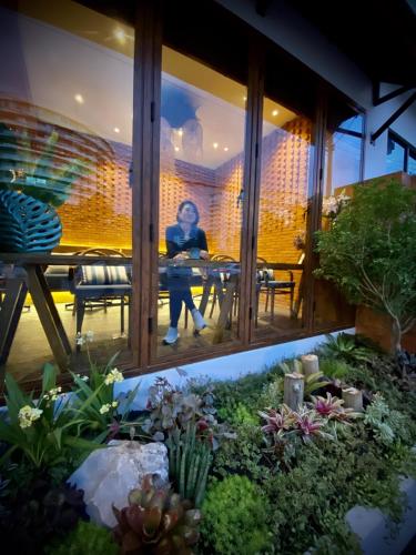 a woman sitting in a window in a garden at Salee Boutique Hotel in Chiang Mai