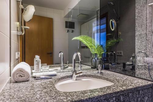 a bathroom counter with a sink and a mirror at SEEhotel Friedrichshafen in Friedrichshafen