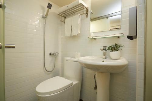 a white bathroom with a toilet and a sink at Shanghai Meego Qingwen Hotel in Shanghai
