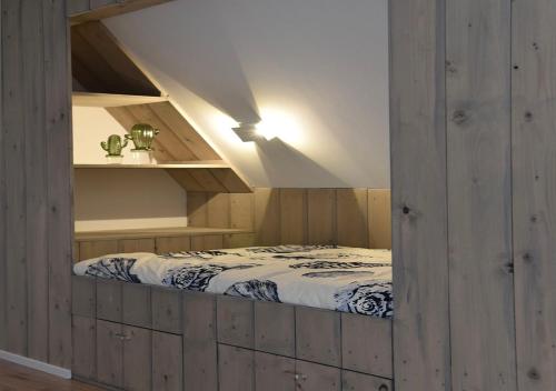 een slaapkamer met een bed in een kamer met houten wanden bij Sfeervol vakantiehuis in Holwerd in Holwerd