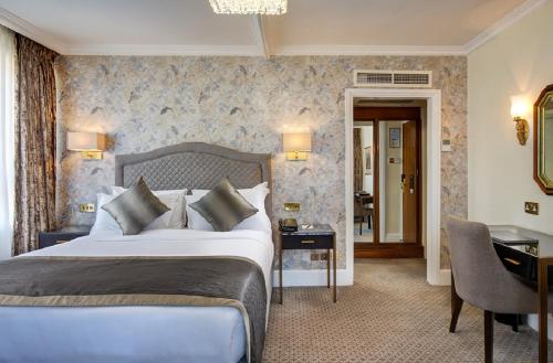 um quarto de hotel com uma cama grande e uma secretária em The Rathbone Hotel, Fitzrovia em Londres