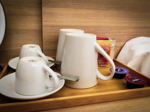 three white coffee mugs sitting on a shelf at My Maison 109 Guest House in Rome