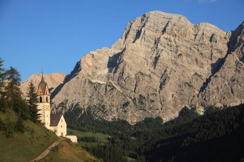a church on a hill in front of a mountain at Lüch de Martin in La Valle