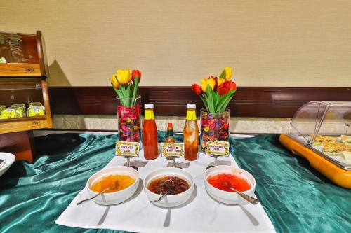 a table with bowls of food and bottles and flowers at Telal Hotel Apartments in Dubai