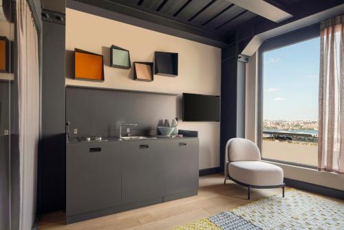Stay Lab Residence & Hotel في إسطنبول: مطبخ مع حوض وكرسي ونافذة