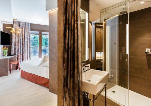 a bathroom with a sink, mirror, and shower at Axel Hotel San Sebastián - Adults Only in San Sebastián