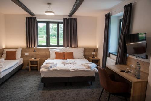 a hotel room with a bed and a desk and a television at Resort Orsino in Horní Planá