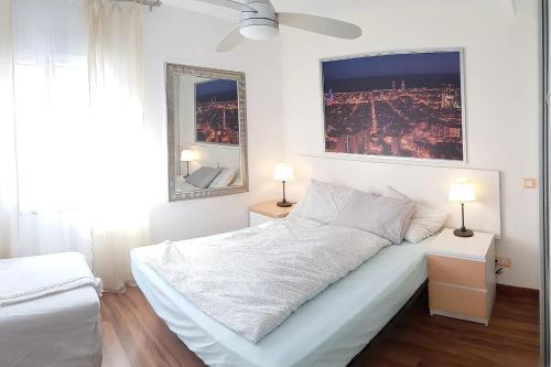 a white bedroom with a large bed and two lamps at Apto. luminoso-6PAX-WIFI-15'/tren Plaza Catalunya in Sant Adria de Besos