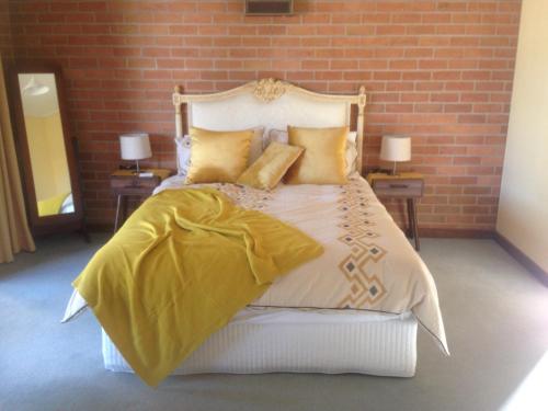 una camera da letto con letto, lenzuola e cuscini gialli di Dunolly Broadway B&B a Dunolly