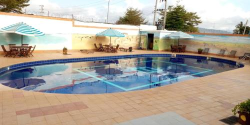 a swimming pool with umbrellas and tables and chairs at Miryams Village Inn Safari Lodge in Sultan Hamud