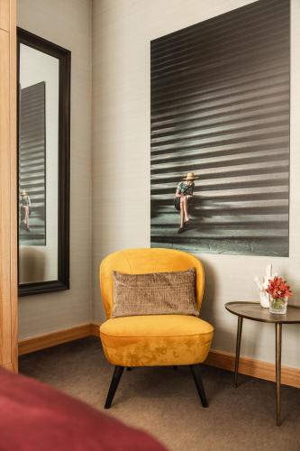 a yellow chair in a room with a painting of a woman at The Delphi - Amsterdam Townhouse in Amsterdam