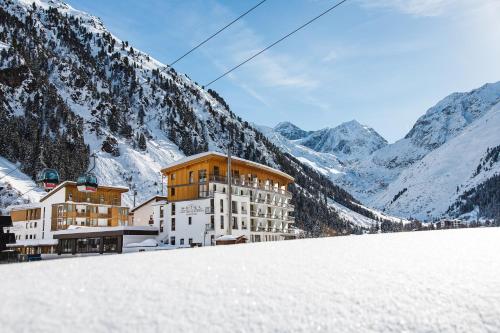 a hotel in the mountains with snow on the ground at DAS VIER Sport,- und Wellnesshotel in Sankt Leonhard im Pitztal