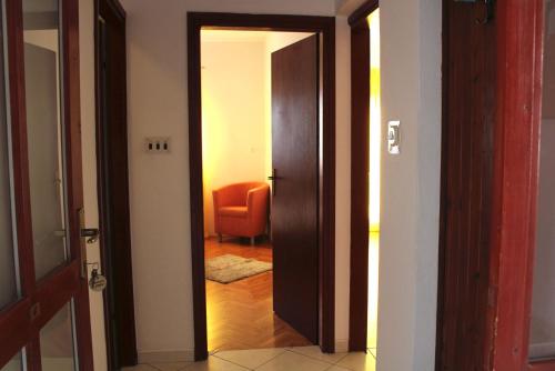 una puerta abierta a un pasillo con una silla naranja en Apartments Luna, en Pag