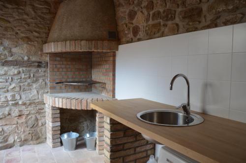een keuken met een wastafel en een bakstenen oven bij Cal Puó Turismo Rural in Collsuspina