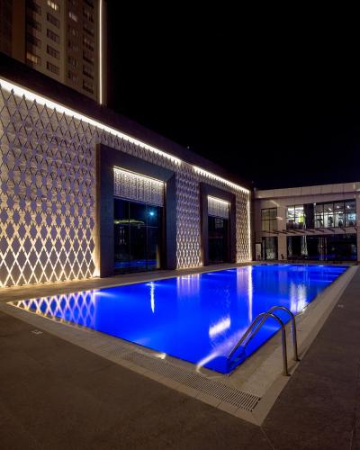 duży basen z błękitną wodą w nocy w obiekcie Prime Suites w mieście Biszkek
