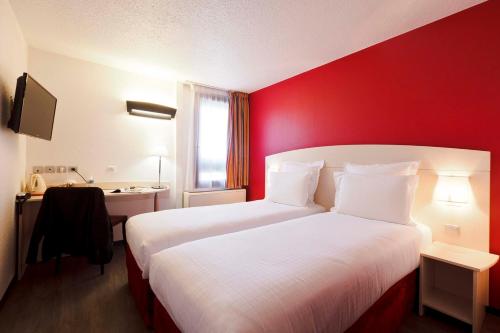 ein Hotelzimmer mit 2 Betten und einer roten Wand in der Unterkunft Kyriad Lyon Sud - Saint Genis Laval in Saint-Genis-Laval