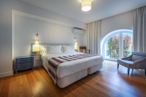 a bedroom with a bed, chair and a window at My Suite Lisbon Guest House – Principe Real in Lisbon