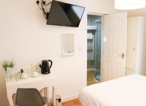 um quarto com uma cama e uma televisão na parede em The Queen's Head Hotel em Buxton
