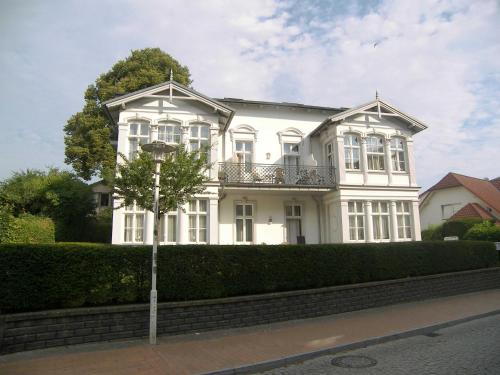 Una casa blanca con un árbol delante. en Villa Baroni BF nur 200m vom Ostseestrand entfernt en Bansin
