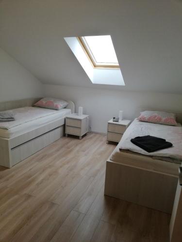 Dieses weiße Zimmer verfügt über 2 Betten und ein Dachfenster. in der Unterkunft Slavuj in Novi Sad