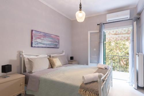 a white bedroom with a bed and a window at Stylish, comfy apartment by Konnect, Corfu city center in Corfu