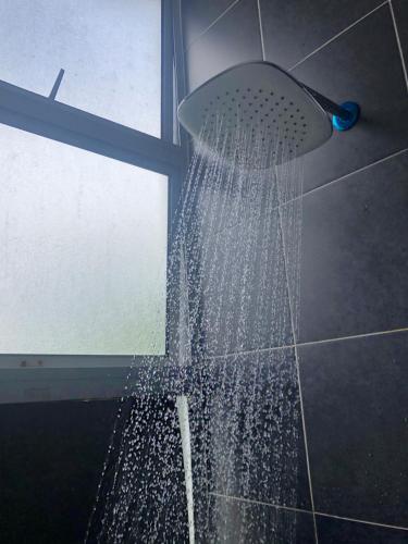 a shower in a bathroom with water coming out of it at A5 Barrington Square 1 Room Apartment in Cameron Highlands