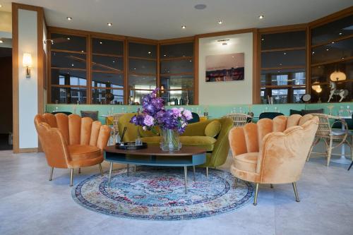 a lobby with chairs and a table with a vase of flowers at Best Western Plus Paris Saclay in Saclay