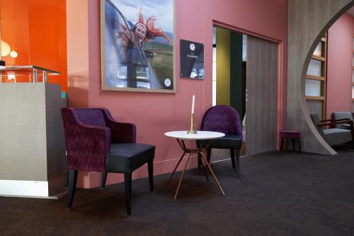 a room with two chairs and a table and a wall at Best Western Plus Paris Saclay in Saclay