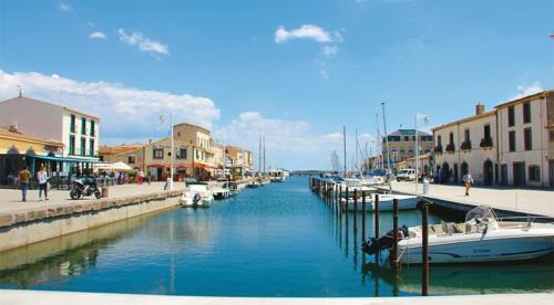 a river with boats docked in a town with buildings at L èphéjules in Marseillan