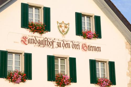 a white building with green shuttered windows and flowers at Landgasthof zu den drei Sternen in Brunegg