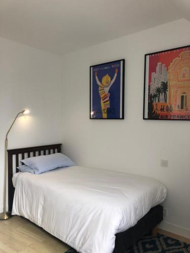 une chambre avec un lit avec deux tableaux au mur dans l'établissement Le Pressoir de la Gervaiserie - 300m de la plage, à Réville