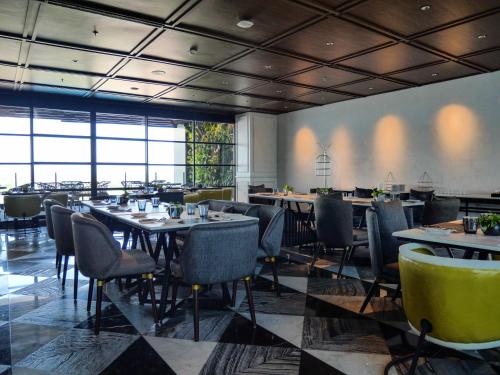 a restaurant with tables and chairs in a room at Movenpick Surabaya City in Surabaya