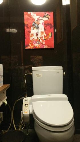 un aseo blanco en un baño con una pintura en la pared en Home Sharing Guest House Don en Takayama
