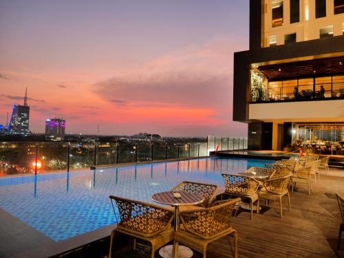 a rooftop bar with tables and chairs on a building at Movenpick Surabaya City in Surabaya