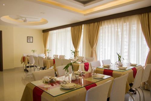 - une salle à manger avec des tables, des chaises et des rideaux dans l'établissement Hotel Park Riviera, à Guwahati