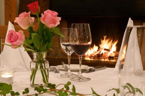 two glasses of wine on a table with a fireplace at Landgasthof zu den drei Sternen in Brunegg