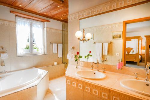 La salle de bains est pourvue de 2 lavabos, d'une baignoire et d'un grand miroir. dans l'établissement Romantik Hotel zu den drei Sternen, à Brunegg