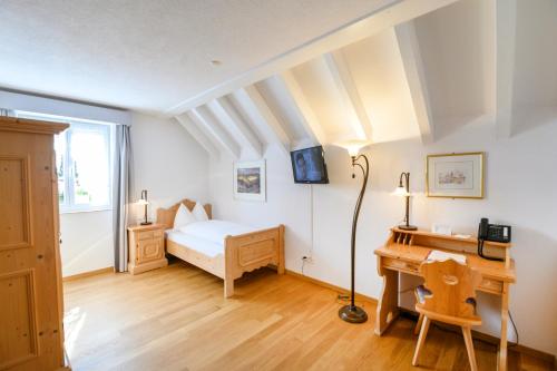 een slaapkamer met een bed en een bureau bij Romantik Hotel zu den drei Sternen in Brunegg