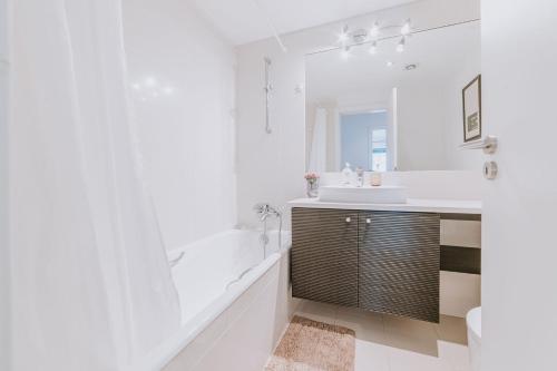 a white bathroom with a tub and a sink at Cozy T2 with Ocean View in Funchal