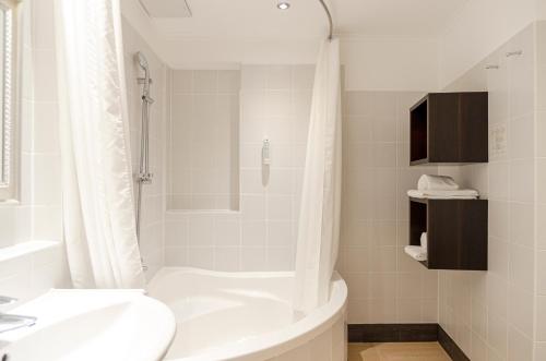 
a white bath tub sitting next to a white sink at Hotel Spiess & Spiess in Vienna
